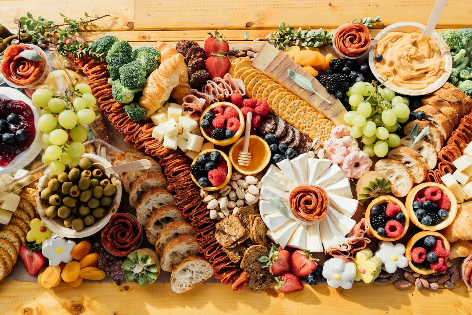 A wooden board with cured meats, cheeses, olives and bread, seen from above