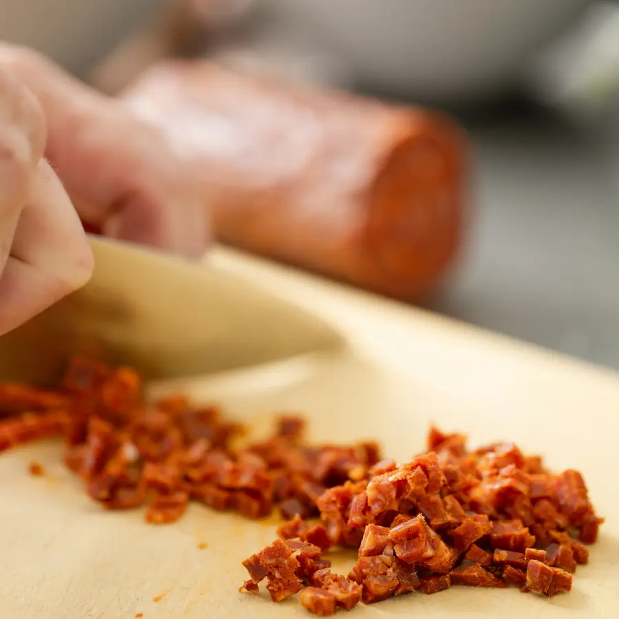 Chorizo ibérico troceado sobre una tabla de madera