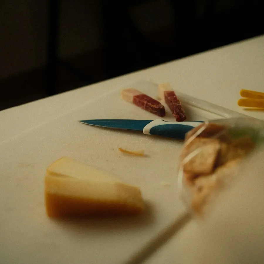 Una cuña de manchego curado sobre una tabla blanca junto a un cuchillo