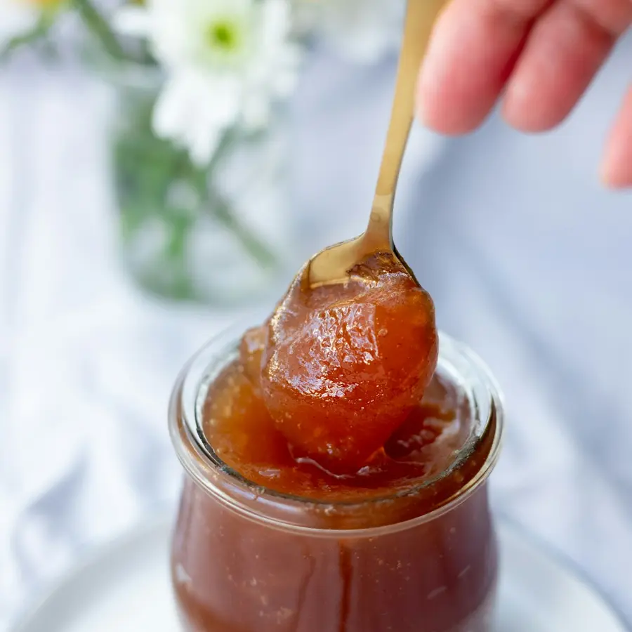 Un tarro de dulce de membrillo con una cuchara
