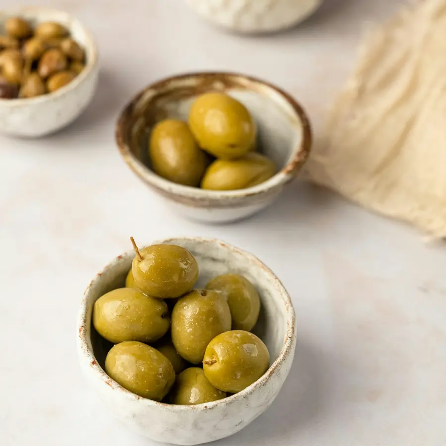 Cuencos de cerámica con aceitunas verdes sobre una mesa clara
