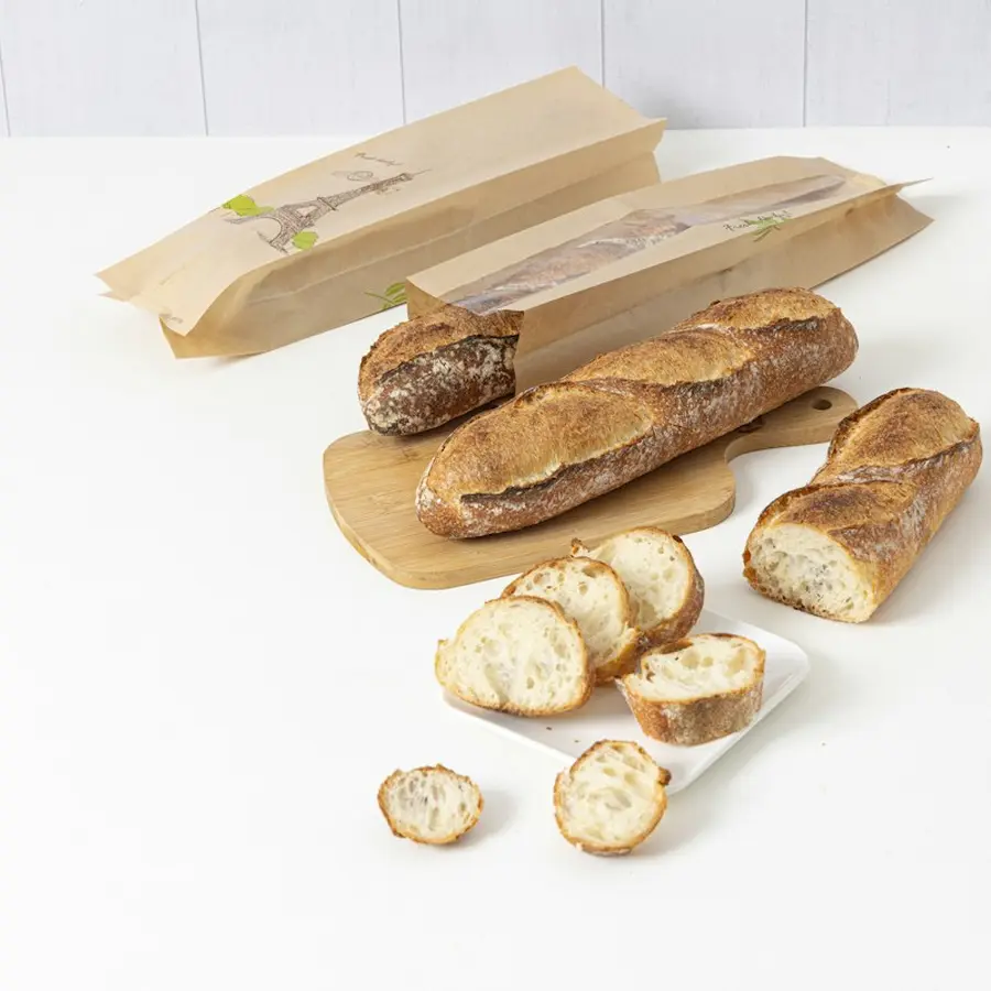 Barras de pan recién hechas y rebanadas sobre una mesa blanca