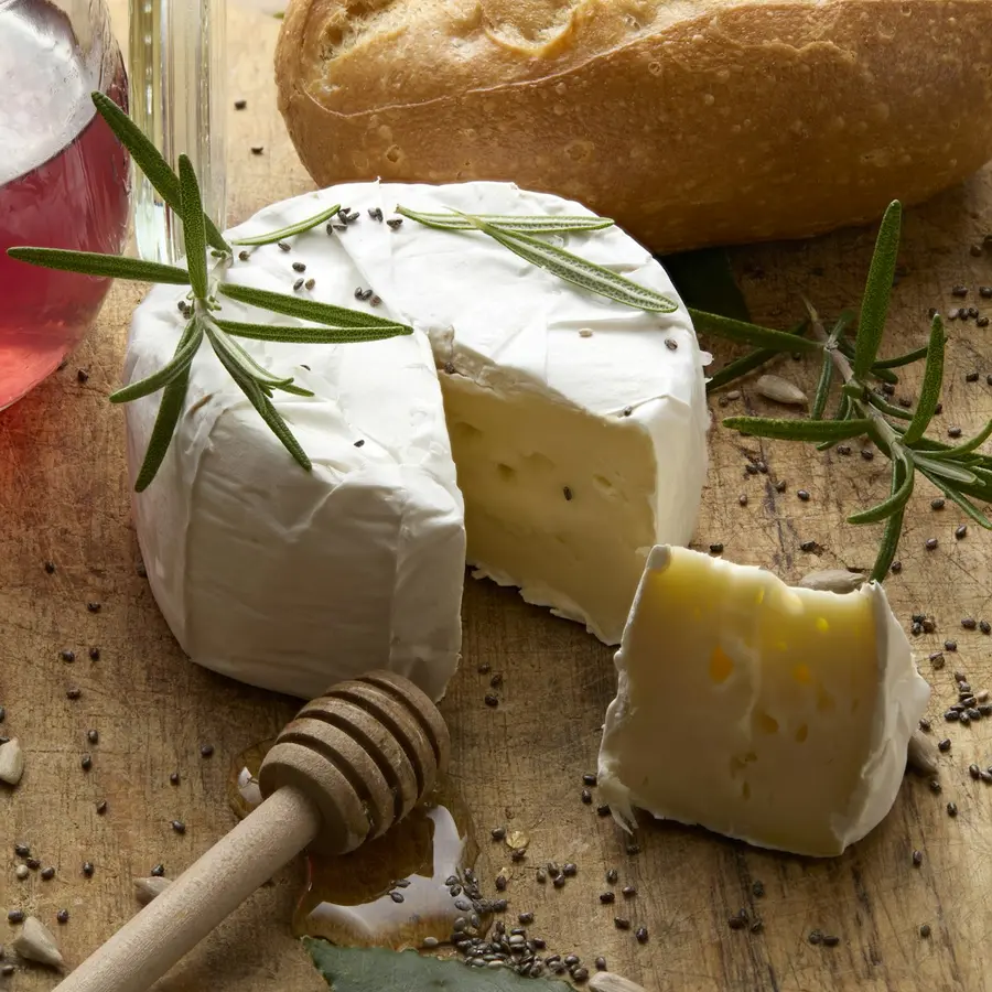Queso cremoso con pan y miel sobre una tabla de madera